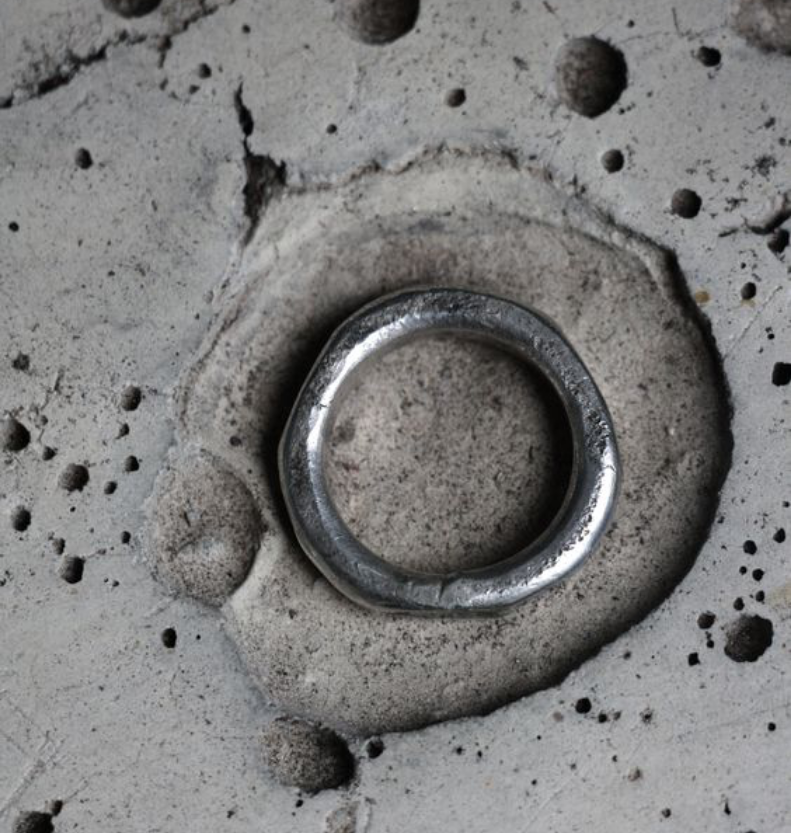 silver ring displayed on organic concrete type texture